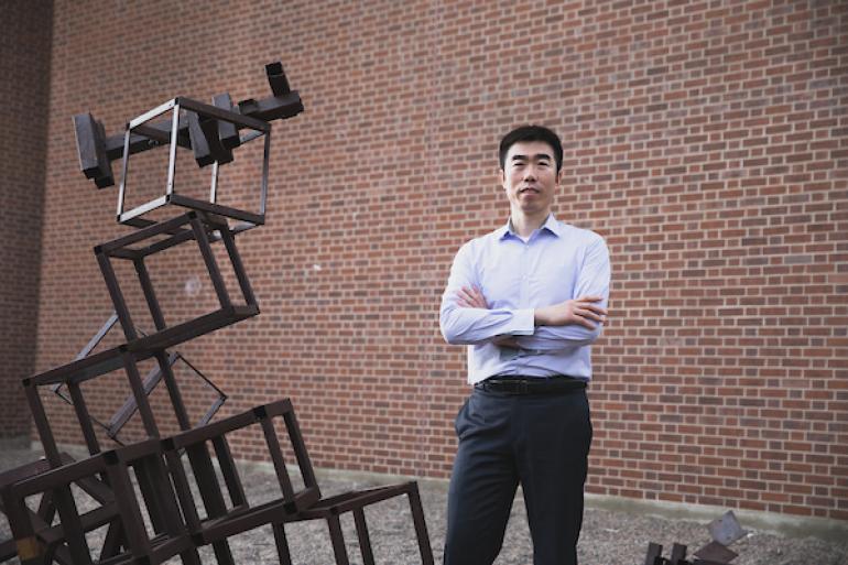 Professor De Liu posing with a sculpture. 